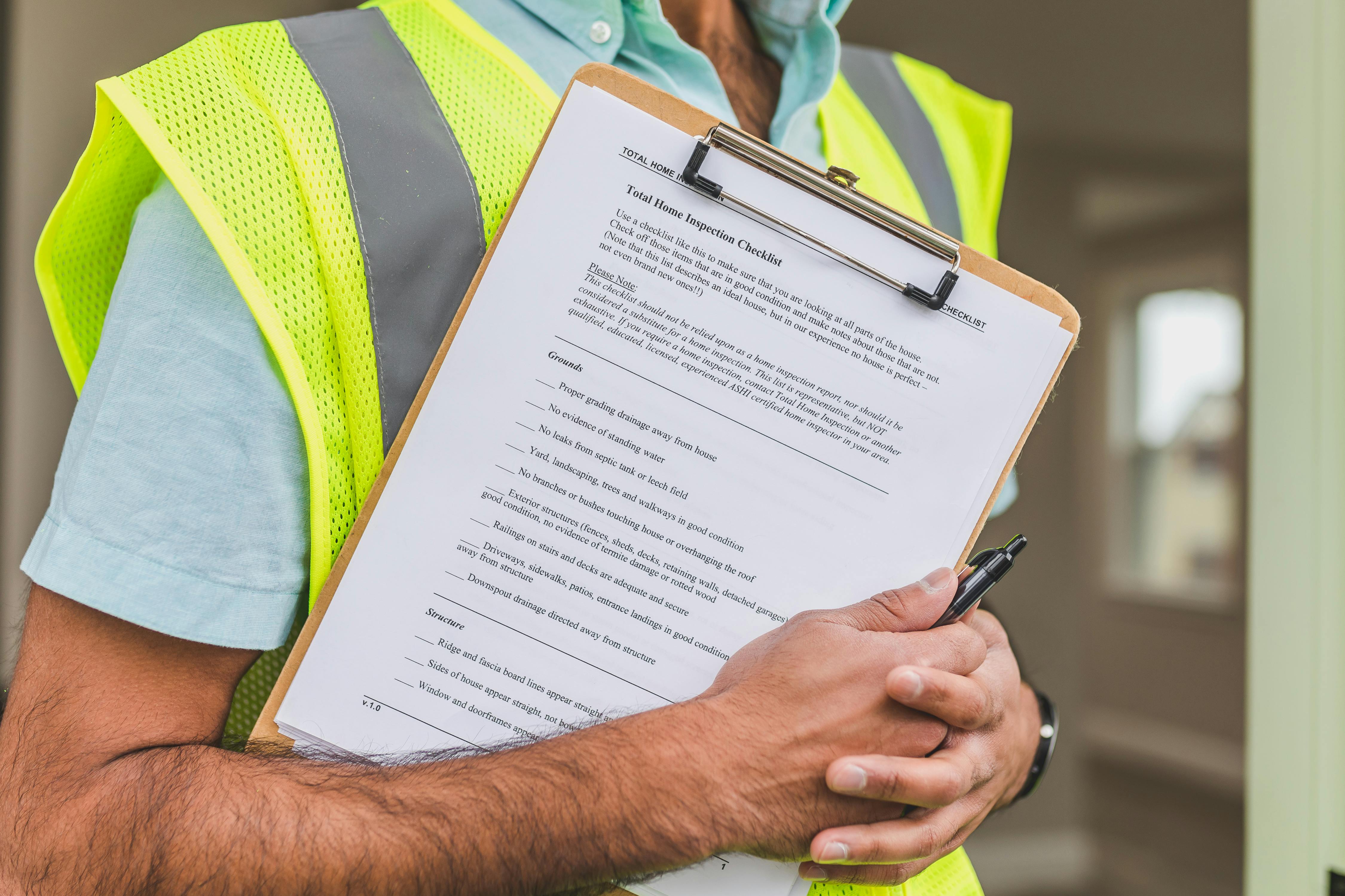 A person in a hi-vis jacket, using a clipboard and pen - close up.